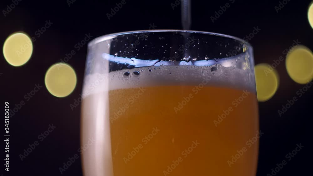 Closeup slowmotion pouring lager beer in the glass on dark background Closeup slowmotion pouring lager beer in the glass on dark background