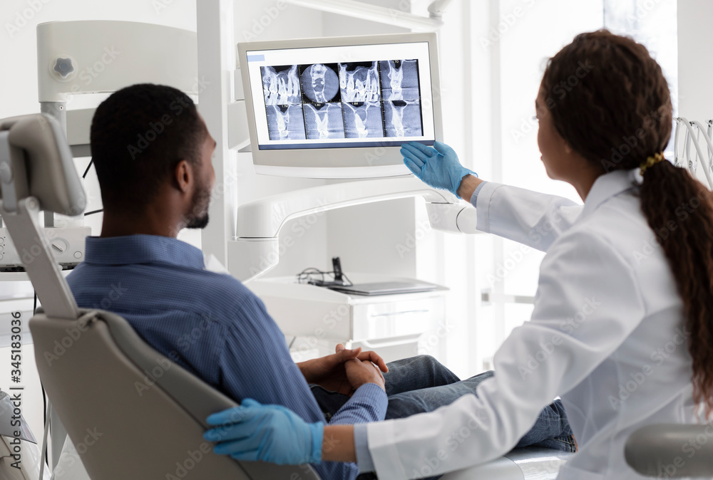 Obraz premium Female dentist pointing at screen with xray picture