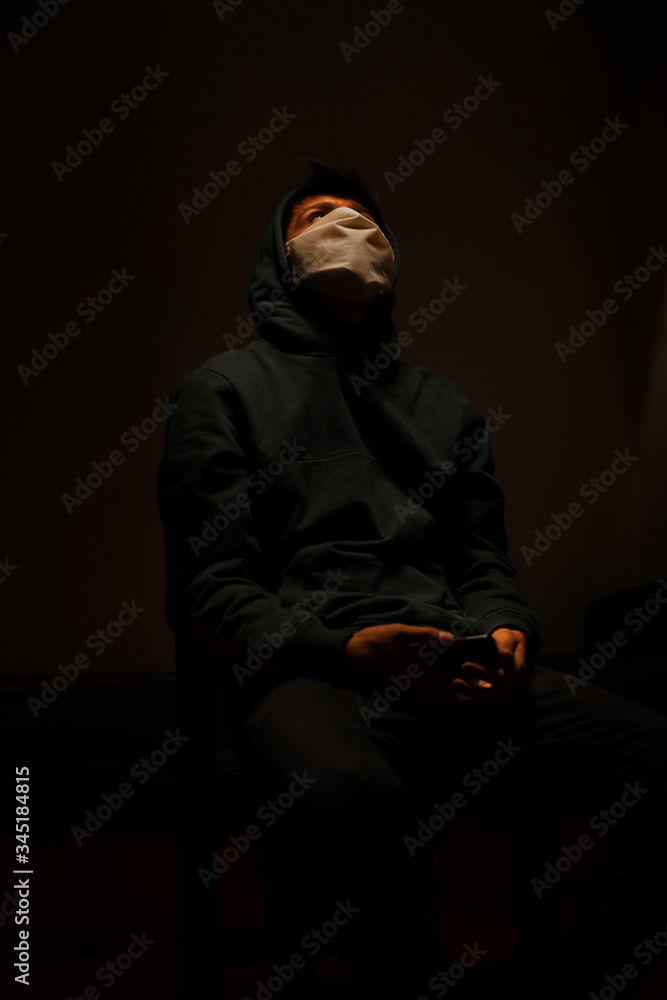 Young man with mask quarantined under light Young man with mask quarantined under light