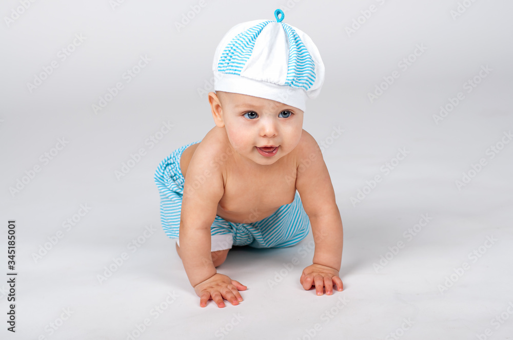 Cheerful baby boy in the sailor white-blue striped cap and shorts Cheerful baby boy in the sailor white-blue striped cap and shorts