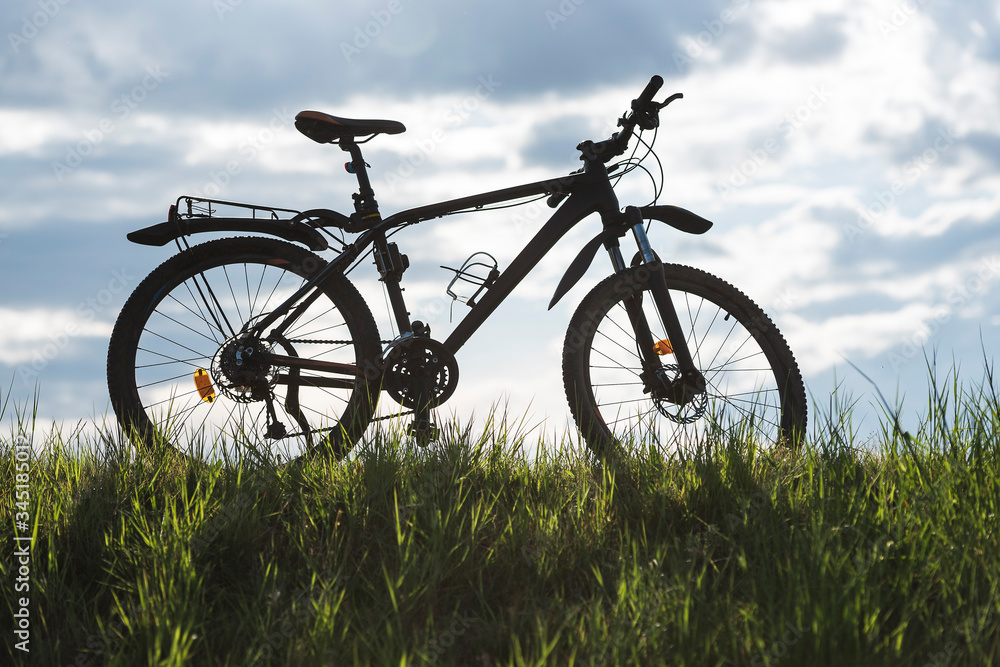 Mountain bike stands on the grass with blue sky in the background Mountain bike stands on the grass with blue sky in the background