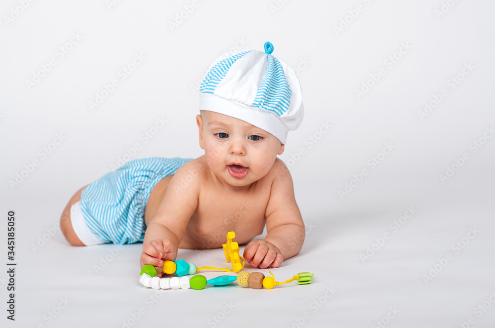 Cheerful baby boy in the sailor white-blue striped cap and shorts Cheerful baby boy in the sailor white-blue striped cap and shorts