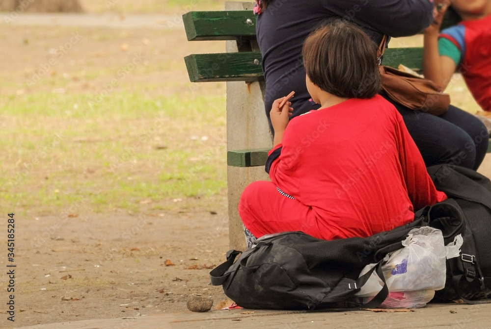 A girl in a red dress, Syrian refugees resting in a park near the bus station and waiting for the transport to the European Union