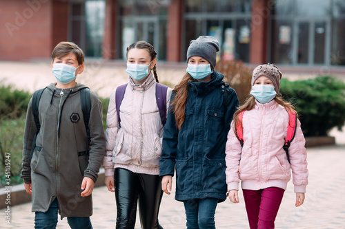 Children students in medical masks leave the school.