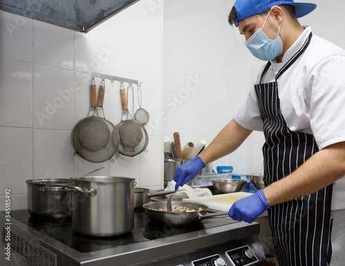 Man in protective mask and gloves cooking on kitchen