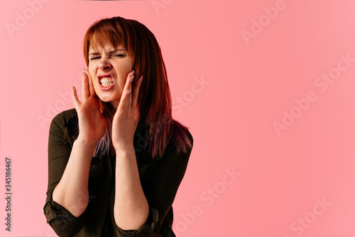 Young angry woman shouting holding her hands near the mouth isolated on pink backgroud