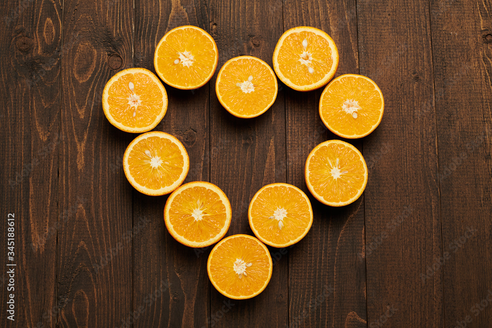 dark wooden background with blank space for text and fresh sliced orange fruits as a heart shape - natural and healthy food. dark wooden background with blank space for text and fresh sliced orange fruits as a heart shape - natural and healthy food.