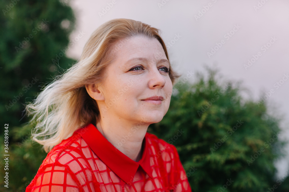 beautiful woman in red blouse. wrinkles on woman's face. blonde in a red blouse. a good looking mom beautiful woman in red blouse. wrinkles on woman's face. blonde in a red blouse. a good looking mom