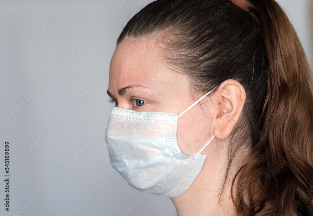 Young woman demonstrates hot to properly wear a face mask covering mouth, nose and chin, to prevent the spread of coronavirus covid-19 in droplets, side view Young woman demonstrates hot to properly wear a face mask covering mouth, nose and chin, to prevent the spread of coronavirus covid-19 in droplets, side view