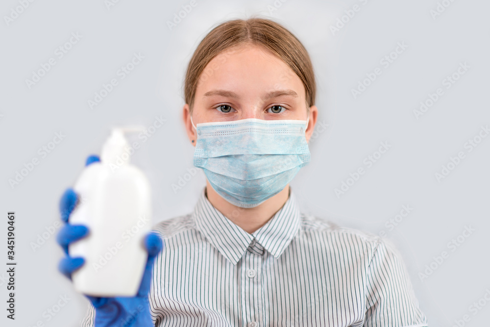 teenager girl, medical mask covers her face, holds antiseptic hand, liquid soap, white background, care help remind patients about safety, COVID-19 pandemic virus outbreak protection concept. teenager girl, medical mask covers her face, holds antiseptic hand, liquid soap, white background, care help remind patients about safety, COVID-19 pandemic virus outbreak protection concept.