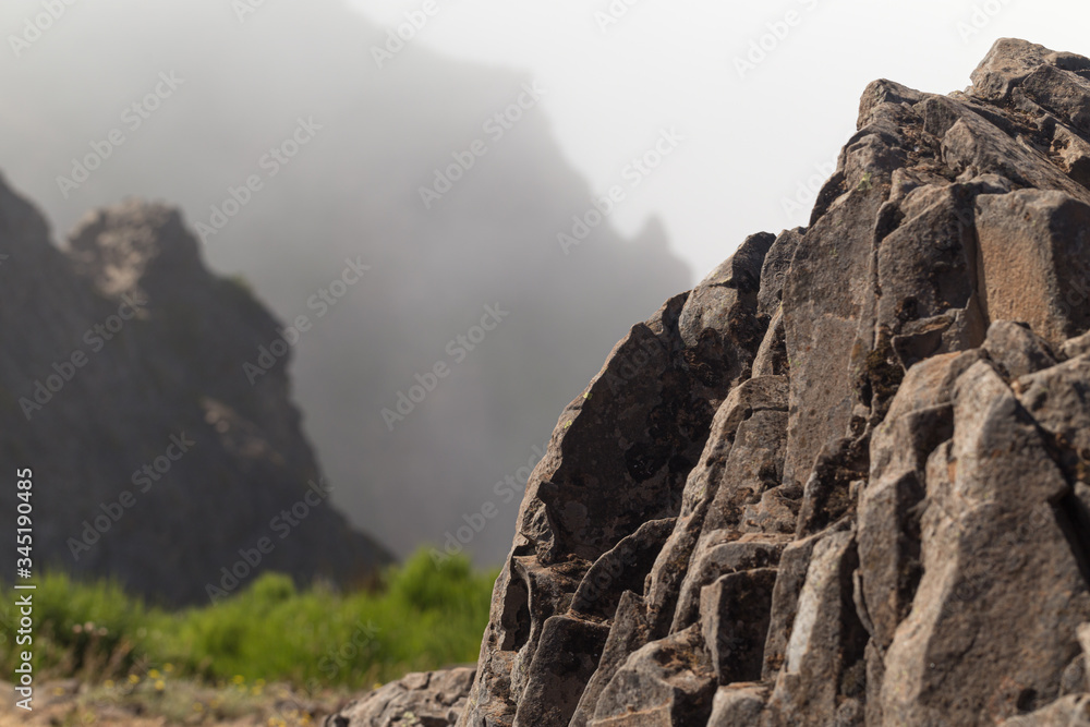 Stone cliffs against the backdrop of the tops of mountains in the fog and blue sky.