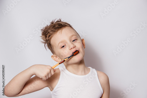 Boy brushes his teeth with a toothbrush on a white background