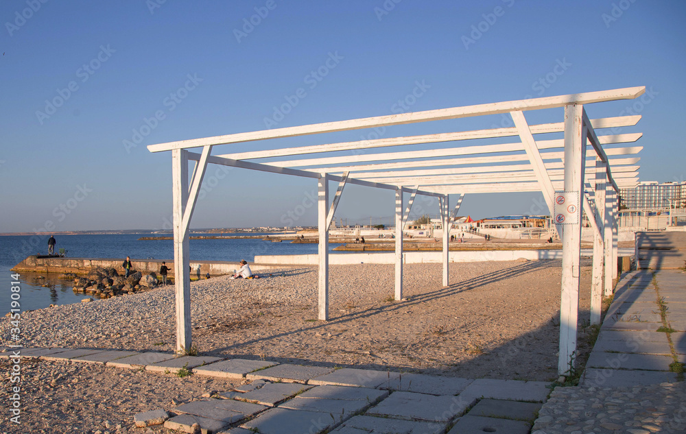 White wooden canopy from the sun's rays to create shadows is by the sea. The concept of a healthy holiday by the sea.
