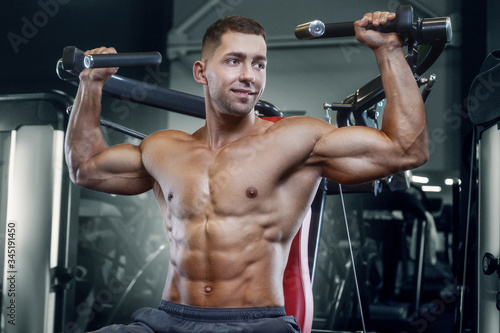 Bodybuilder strong man pumping up shoulder muscles