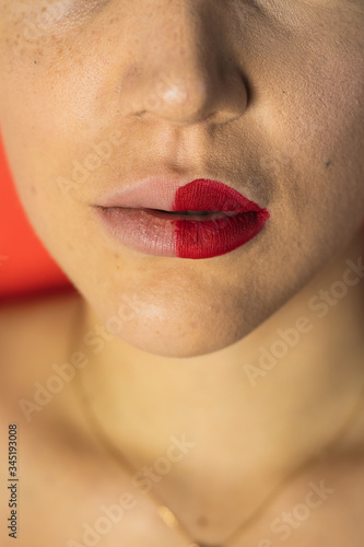 Close up of female lips with two different lipsticks. Red background