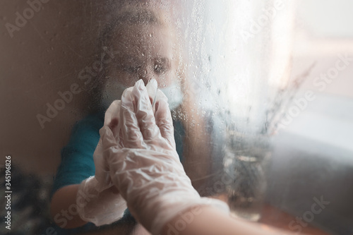 The girl holds out her hand in a protective glove to the glass. The other hand is in a protective glove on the other side of the glass. Shooting through the glass. Selective focus