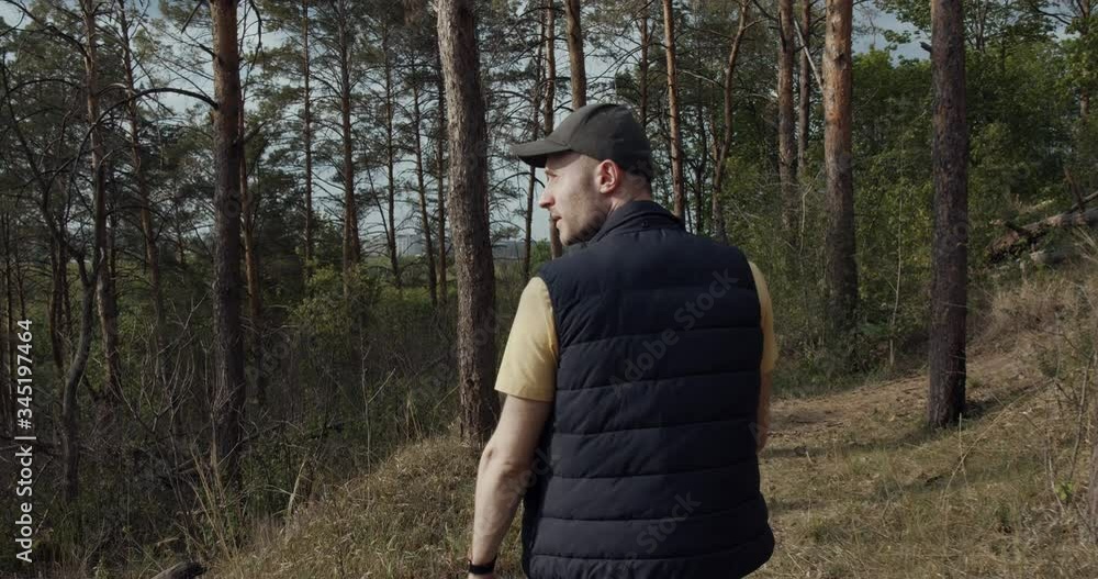 Man with a hat walks in the forest, with a backpack. Back View of Walking Person. Adventure Trip in Natural Landscape. Man with a hat walks in the forest, with a backpack. Back View of Walking Person. Adventure Trip in Natural Landscape.