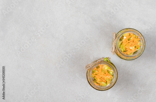 Cabbage salad with carrots in a jar on a light background top view