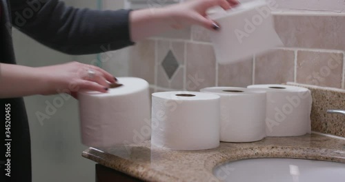 Female Unstacking Toilet Paper in Bathroom photo