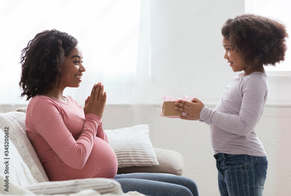 Pregnant Black Mom Receiving Gift From Her Little Daughter At Home Pregnant Black Mom Receiving Gift From Her Little Daughter At Home