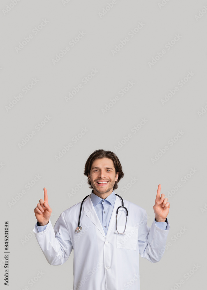 Handsome male doctor pointing fingers at copy space above his head Handsome male doctor pointing fingers at copy space above his head