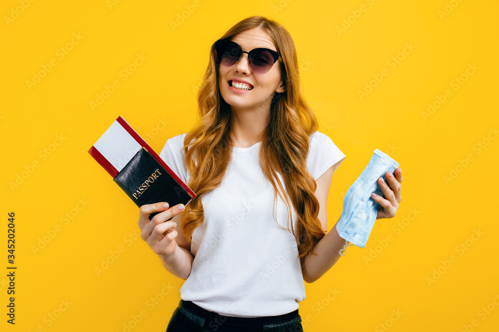 A girl in sunglasses with a passport and tickets and a protective medical mask in her hands, goes abroad. Concept of travel, quarantine and coronavirus A girl in sunglasses with a passport and tickets and a protective medical mask in her hands, goes abroad. Concept of travel, quarantine and coronavirus