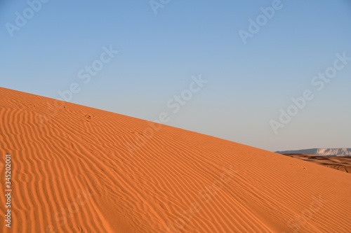 Red sand in the Arabian desert and mountain top at the background (Tuwaiq). In Saudi Arabia near Riyadh (Mozahmeia area)