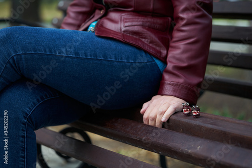 A woman in a park sits on a bench on which are figures of the virus