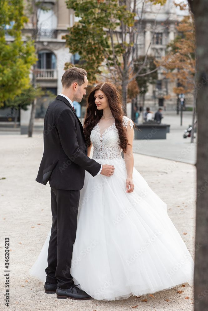 Bride and groom dancing in the old town street. Wedding couple walks in Budapest near Parliament House. Caucasian happy romantic young couple celebrating their marriage. Wedding and love concept. Bride and groom dancing in the old town street. Wedding couple walks in Budapest near Parliament House. Caucasian happy romantic young couple celebrating their marriage. Wedding and love concept.