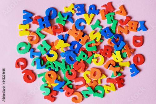 Fotografie multicolored letters of the English alphabet mixed on a pink background