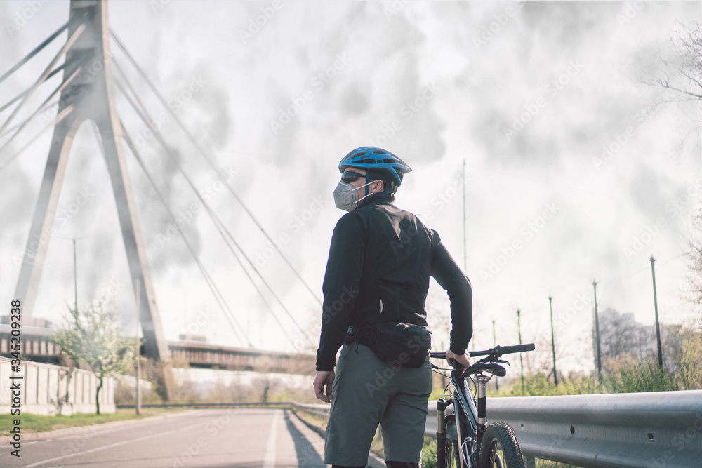 Male cyclist wearing respirator face mask with heavy duty protective filter. Man on bike wearing respirator face mask with heavy duty protective filter. Safety breathing masks. Pollution concept