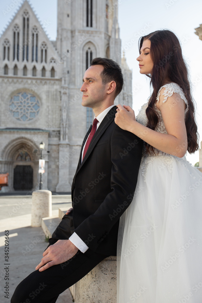 Bride and groom hugging in the old town street. Wedding couple walking on the Fisherman's Bastion, Budapest, Hungary. Happy romantic young couple celebrating their marriage. Wedding and love concept. Bride and groom hugging in the old town street. Wedding couple walking on the Fisherman's Bastion, Budapest, Hungary. Happy romantic young couple celebrating their marriage. Wedding and love concept.