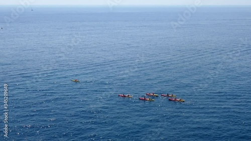 Long shot aerial shot of a large group of sea kayakers following their leader in the open sea