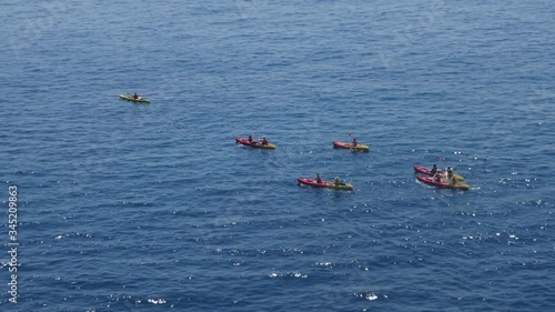 Long shot aerial shot of a large group of sea kayakers following their leader in the open sea