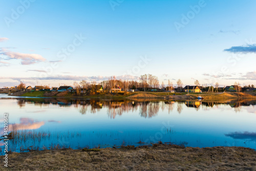 urban village or village with wooden houses located on the blue river bank, early spring evening at sunset