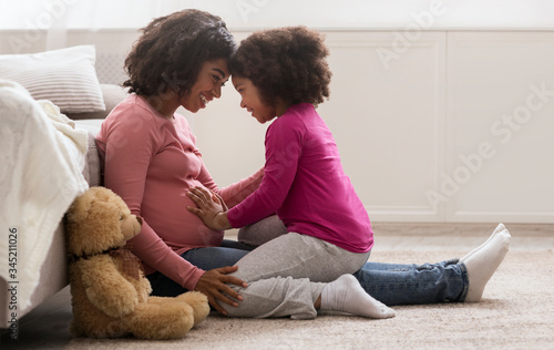 Happy Pregnant Black Woman And Her Cute Daughter Bonding At Home