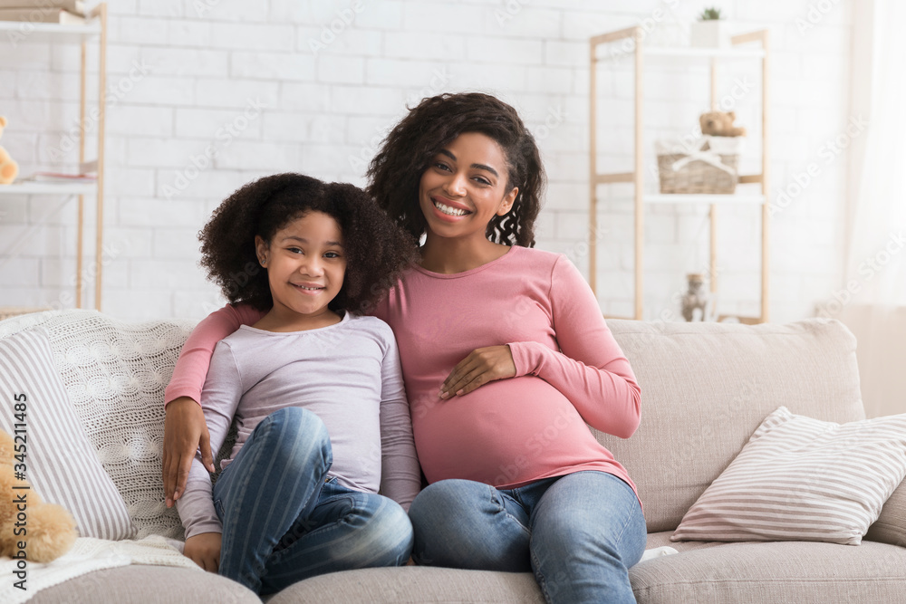 Happy pregnant african woman and her little daughter relaxing at home Happy pregnant african woman and her little daughter relaxing at home