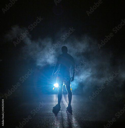 Mysterious figure in front of smoky car headlights © Luke