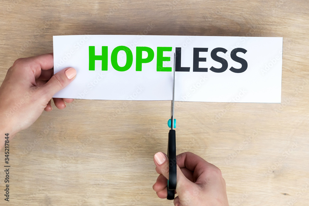 Woman hands hold paper with the word Hopeless, cut it with scissors to make Hope. Woman hands hold paper with the word Hopeless, cut it with scissors to make Hope.