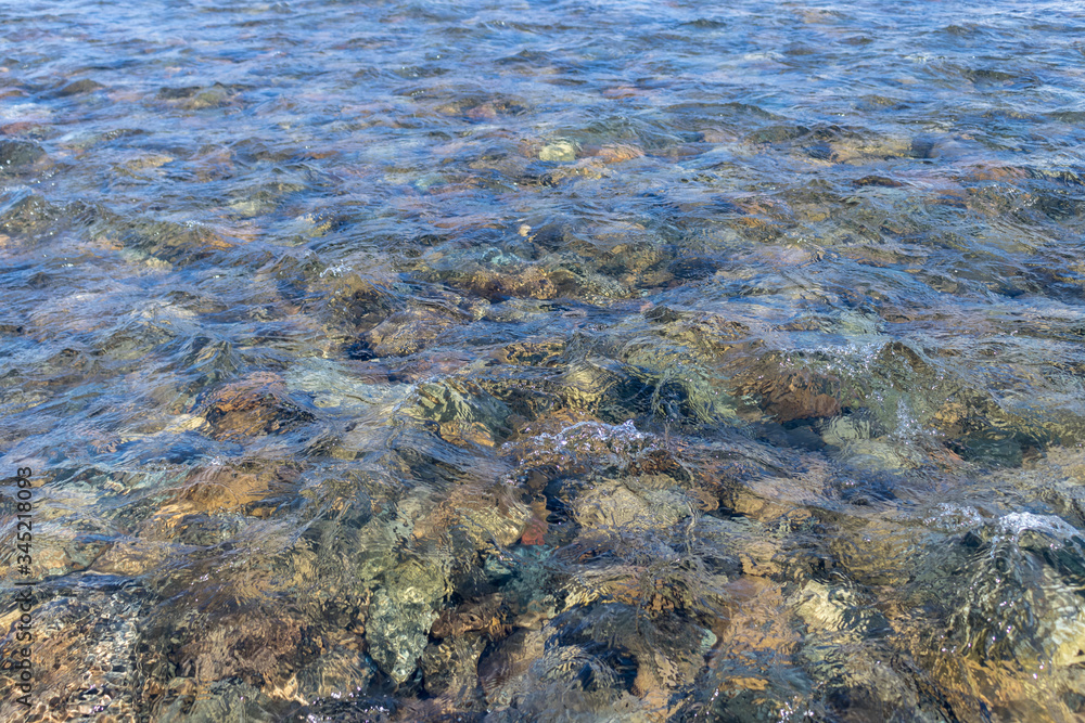 Ripples in shallow water - clear cold water and colored stones at the bottom