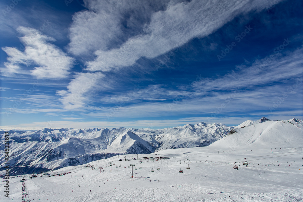 Winter ski resort with ski lifts against the backdrop of mountains and beautiful sky
