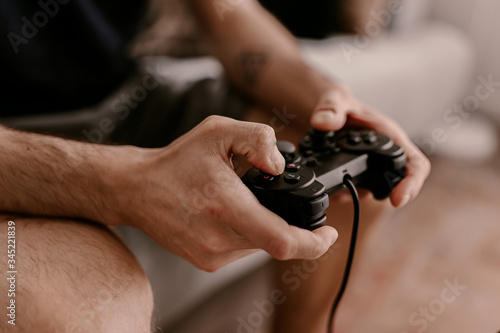 Hipster man plays video games on a couch. Relaxing time. Fun weekend. Concentrated on a video game. Winning the game  gambling. Multiplayer game. Online gaming. Streaming video game. Soccer  racing