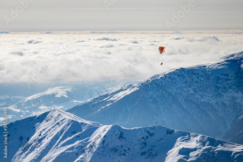 Paraglider flies over the mountain peaks of the Caucasus