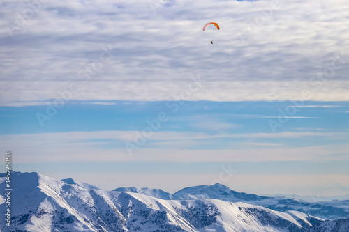 Paraglider flies high above the Caucasus mountains in the clouds