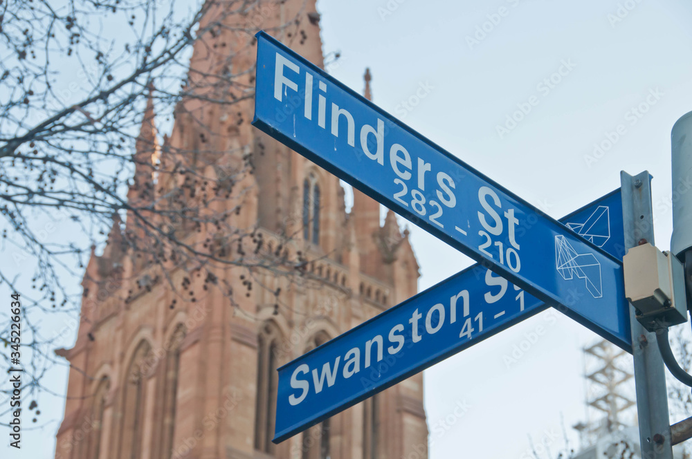 MELBOURNE, AUSTRALIA - JULY 29, 2018: Street signs of Flinders St and Swanston St in front of St Paul's Cathedral in Melbourne central business district near Federation square. MELBOURNE, AUSTRALIA - JULY 29, 2018: Street signs of Flinders St and Swanston St in front of St Paul's Cathedral in Melbourne central business district near Federation square.