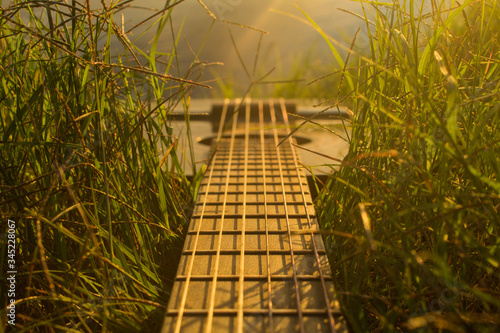 Black guitar in grass at sunset
