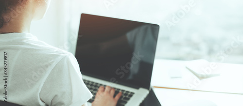 Schilderij op canvas Young woman sitting with laptop in front of big bright window with panoramic view