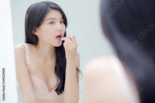 Beautiful young asian woman applying lipstick pink with style bright and shiny on mouth  beauty girl looking mirror for makeup cosmetic with lip elegance  fashion make up with luxury and sexy.