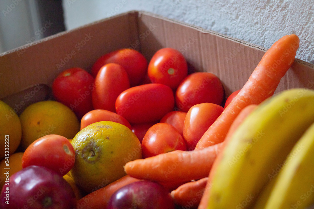 A group of fruits and vegetables in a box, organized by its type and colour