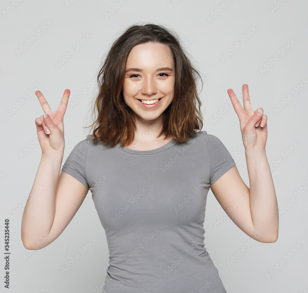 happy girl looking at camera with smile and showing peace sign with fingers happy girl looking at camera with smile and showing peace sign with fingers